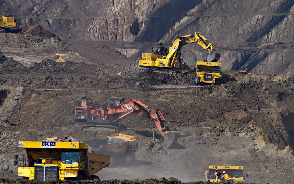 Large-scale open-pit mining operation with excavators and haul trucks working terraced benches